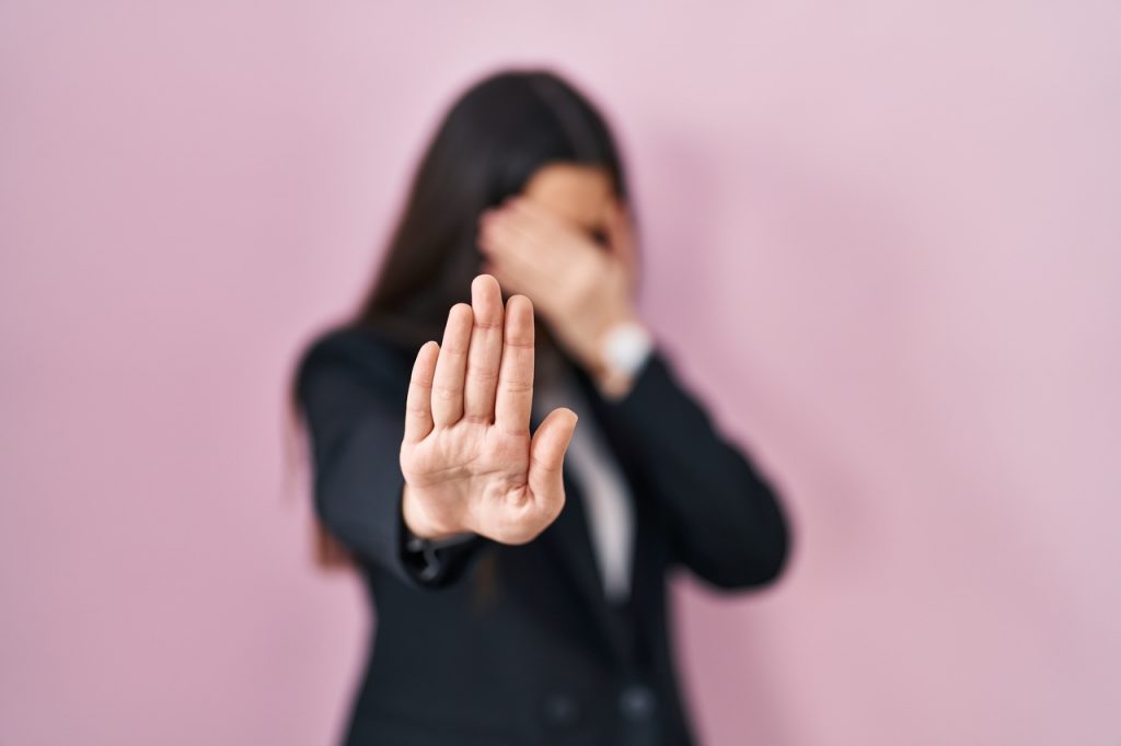 mulher cobre o rosto de denúncia assédio sexual